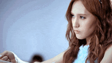 a woman with red hair is wearing a blue dress and looking at something