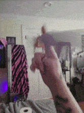 a person with a tattoo on their arm is holding a purple object in their hand .