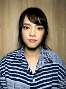 a woman in a striped shirt is looking at the camera .