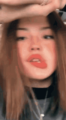 a close up of a woman 's face with red lipstick and a necklace .