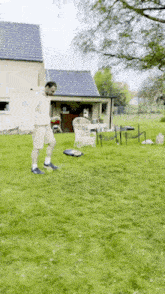 a man is standing on a lush green lawn in front of a house .