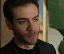 a man with a beard is wearing a black jacket and black shirt
