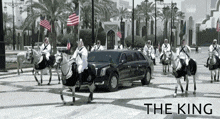 a black and white photo of men riding horses in front of a limousine that says the king
