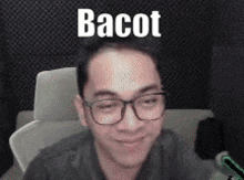 a man with glasses is sitting in a chair with the word bacot on his forehead .