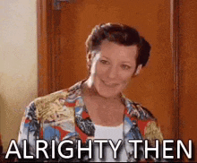 a woman in a hawaiian shirt is standing in front of a door and smiling .