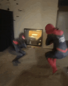 a man in a spiderman costume is squatting down in front of a fireplace