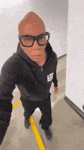 a bald man wearing glasses and a black hoodie that says abbey road shoes
