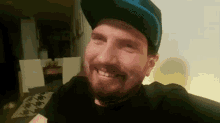 a man with a beard wearing a hat is smiling .
