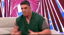 a man is sitting on a couch with his hands on his chest .