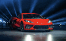 a red sports car is parked in a dark room with a blue light shining on it .