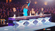 a woman in a blue dress stands in front of a table that says xxx