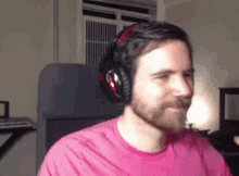 a man in a pink shirt is wearing headphones