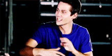a young man in a blue shirt is laughing with his mouth wide open