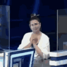 a woman is sitting at a desk with her hands folded in front of a computer .
