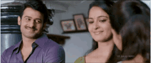a man in a purple shirt stands next to two women with sri balaji video written on the bottom right