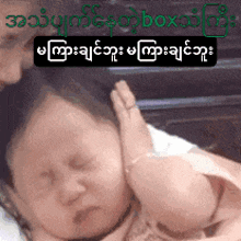 a baby is being held by a woman with foreign writing on the bottom right