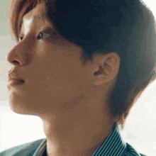 a close up of a man 's face with a striped shirt on and earrings .