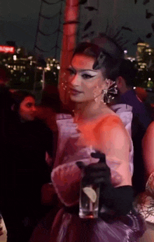 a woman in a purple dress and black gloves is holding a glass of water .