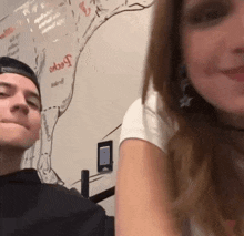 a man and a woman are sitting next to each other in front of a wall with a drawing of a cow on it .