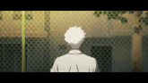 a man stands behind a chain link fence looking at something