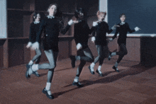a group of young women in black dresses are dancing