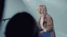 a woman is singing into a microphone while playing a guitar in front of a crowd .
