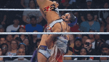two women are wrestling in a ring with a crowd watching and one is wearing a fire outfit