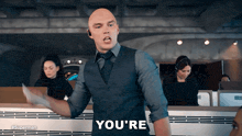 a man in a suit and tie says " you 're " in an office