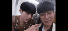 two young men are sitting next to each other on a plane .