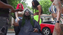 a man with green hair is surrounded by a group of women .