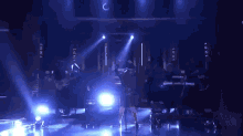 a woman is singing into a microphone on a stage with a band behind her .