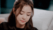 a woman wearing a black shirt and earrings is sitting on a couch with her eyes closed