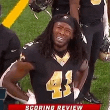 a football player is standing on a field with his hands on his hips and smiling .