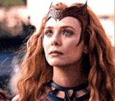 a woman with long red hair is wearing a crown and a necklace .