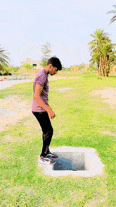 a young man is jumping out of a hole in the grass