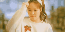 a young woman is wearing a headband and a white sweater .