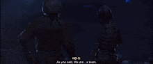 a man in a helmet stands next to another man in a dark room