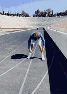 a man in a blue jacket and white shorts stands on a track