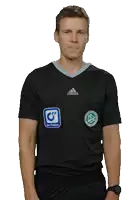 a man wearing a black adidas shirt stands with his hands in his pockets against a white background