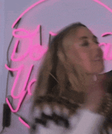 a blurry picture of a woman in front of a pink neon sign that says dior