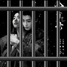 a black and white photo of a man and woman behind bars with chinese writing on it