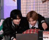 a couple of people are sitting on a couch looking at a laptop .