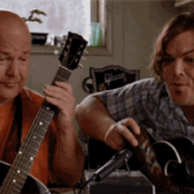 two men are playing guitars in front of a gibson chair