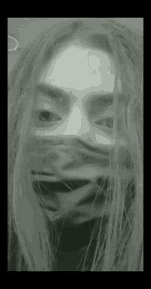 a black and white photo of a woman covering her face with a mask