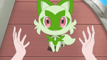 a green and white cartoon cat with pink eyes is being held by two hands