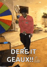a man in a red shirt is dancing in a living room in front of a colorful wheel .