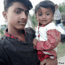 a boy holds a baby in his arms with pixiz written on the bottom right