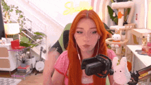 a woman with red hair is sitting in front of a microphone and holding a stuffed animal .