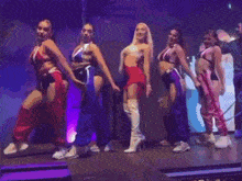 a group of women are dancing on a stage with purple lights in the background