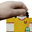 a hand is reaching out towards a yellow shirt with a green bottle on it .
